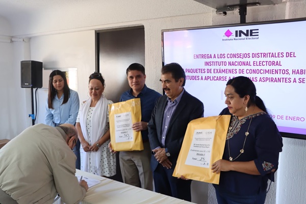 personas sosteniendo sobres amarillos con exámenes de conocimientos