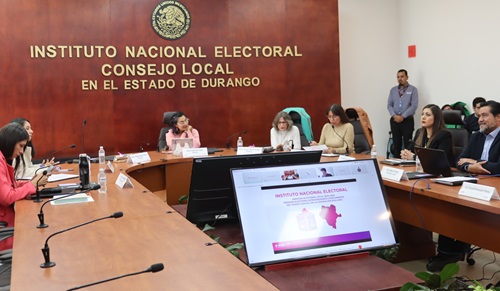 seis personas sentadas en una mesa en el salón de sesiones