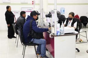 dos personas sentadas en las ventanillas de atención del módulo del INE