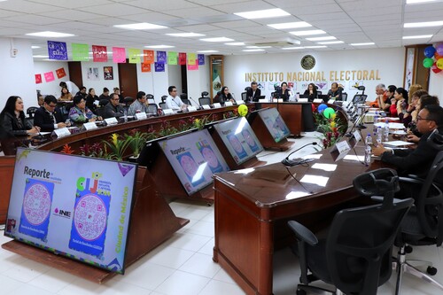 varias personas sentadas en la mesa del salón de sesiones