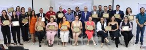 Varias personas de pie y sentadas sosteniendo un reconocimiento en sus manos
