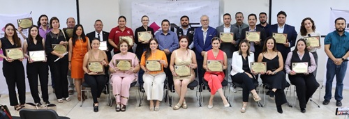 Varias personas de pie y sentadas sosteniendo un reconocimiento en sus manos 