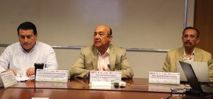 tres personas sentadas en una mesa dialogando con el resto de los presentes