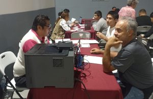 Trabajador del INE orienta a dos personas sobre la obtención de la credencial para votar