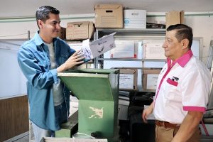 Dos trabajadores del INE parados a lado de una trituradora