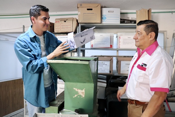 Dos trabajadores del INE parados a lado de una trituradora