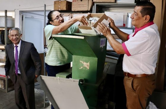 Dos funcionarios del INE vertiendo credenciales para votar a una trituradora para su destrucción
