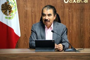 Hombre sentado frente un micrófono y una computadora hablando