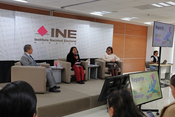 tres personas sentadas en un escenario
