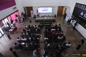 Imagen abierta en el lobby del instituto con las personas participantes paradas al frente de la audiencia.