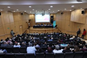 Personas participantes y público asistente al evento, sentados en el auditorio.