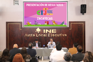 varias personas sentadas en un salón atrás un letrero color rosa