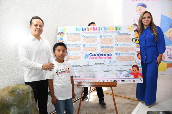 Personas de pie a un costado de un mural con letras de colores