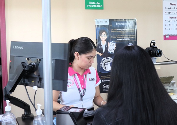 mujer con playera blanca con rosa atendiendo a una persona cabello largo negro