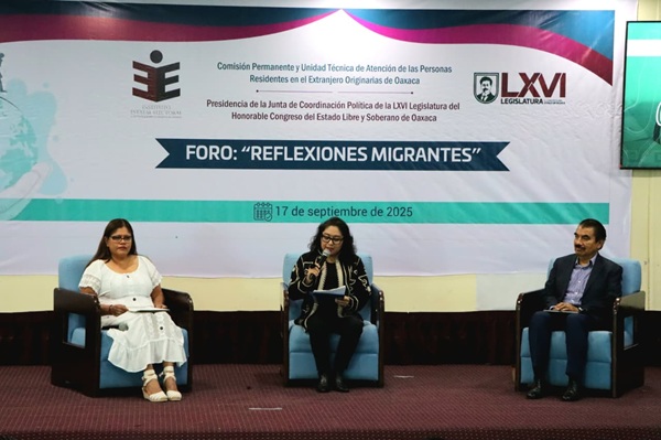 tres personas sentada en el escenario de un auditorio