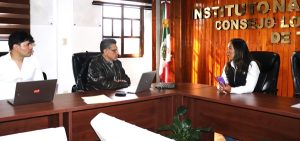 tres personas sentada frente a una mesa color café con computadoras