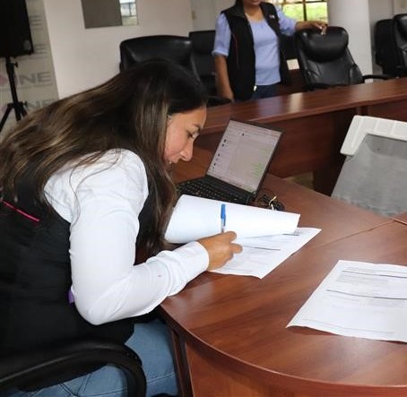 mujer sentada firmando un documento