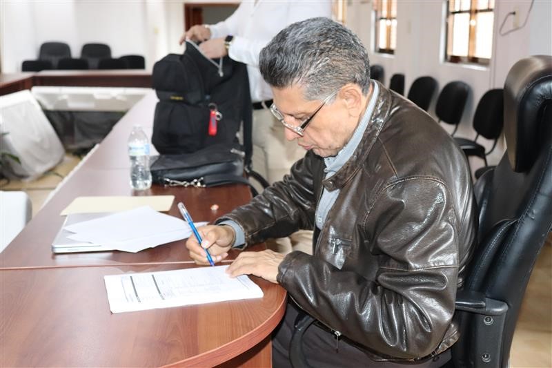 hombre con lentes sentado firmando un documento