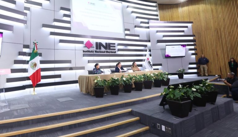 Personas participantes sentadas en el estrado al frente del recinto.