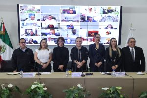 Personas participantes de pie en el estrado frente al público asistente.