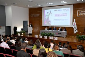 un auditorio con personas sentadas viendo y escuchando a personas en el escenario