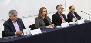 cuatro personas sentadas en una mesa con micrófonos