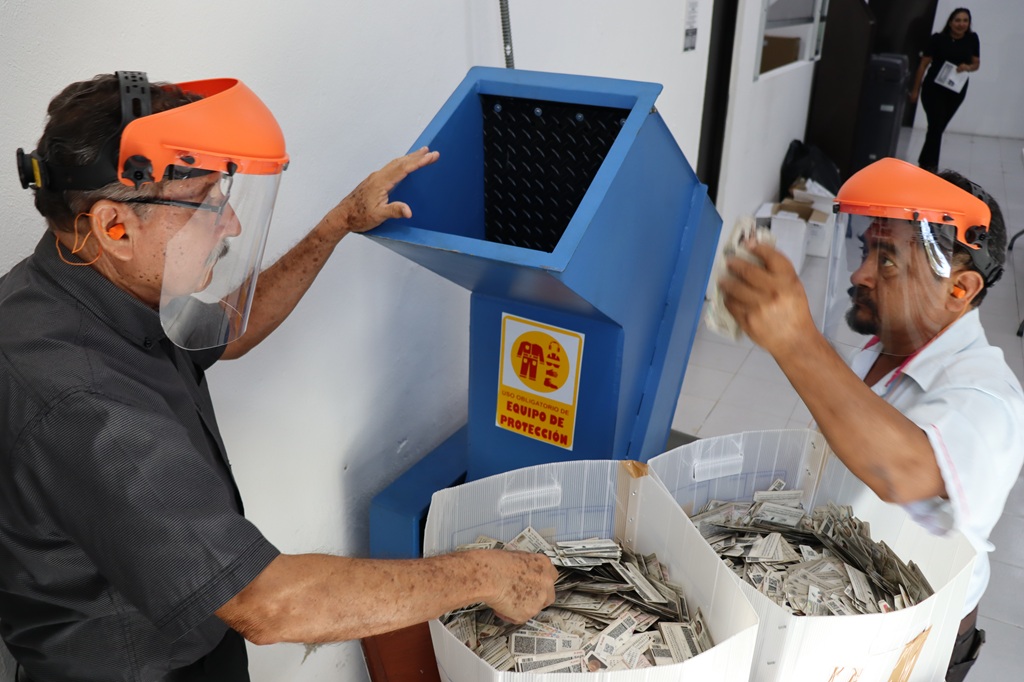 dos hombres con caretas a un costado de una trituradora