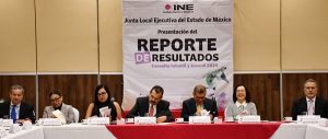 personas en un auditorio sentados frente a una lona con letras negras