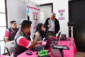 personas con chaleco rosa sentadas frente a computadoras