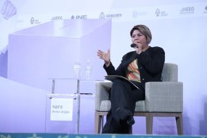 mujer sentada en un sillón hablando mediante un micrófono