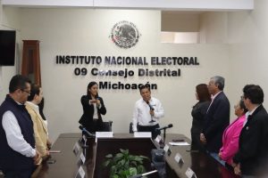 personas de pie, viendo a una mujer con el brazo extendido al frente