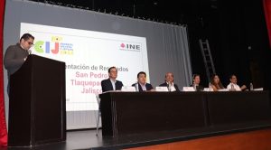 una persona de pie en un pódium y personas sentadas