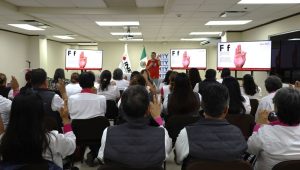 personas sentadas en un salón frente a un maestro y pantallas