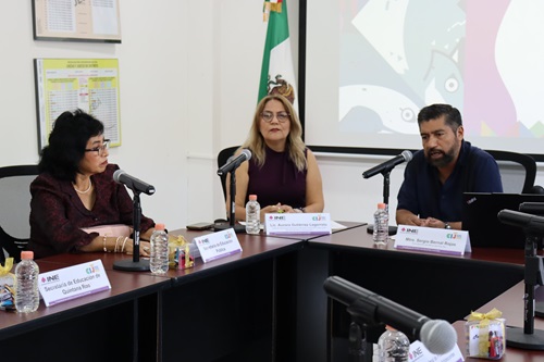 tres personas sentadas frente a una mesa con micrófono