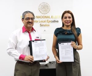 una mujer y un hombre de pie, cada uno sostiene un documento