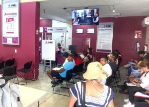 personas sentadas al interior de una oficina del INE
