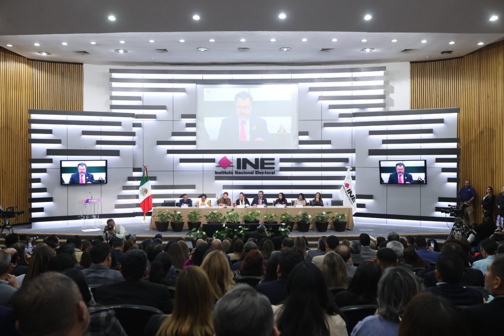 Persona participantes sentadas frente al público asistente en el auditorio del Instituto.