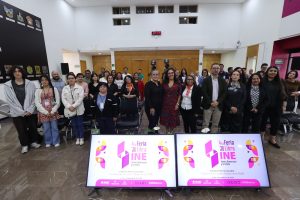 Persona participantes y público asistente paradas en el lobby del Instituto posando para la foto.