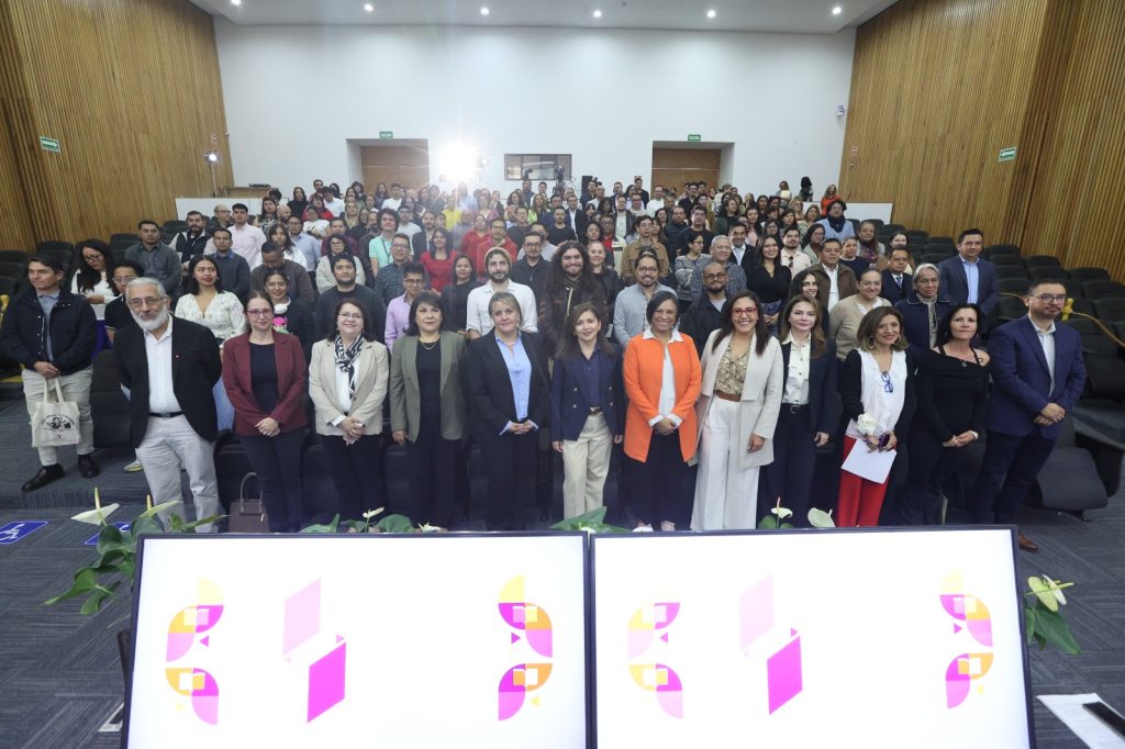 Personas participantes paradas en el auditorio posando para la foto oficial.