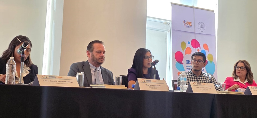 personas sentadas frente a una mesa con micrófono