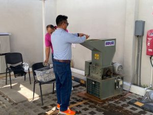hombre de pie frente a una maquina trituradora