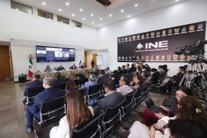 Persona participantes sentadas en el estrado en el lobby del instituto durante su participación en el evento.