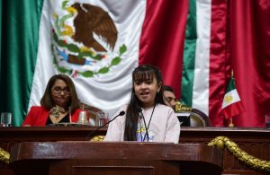 niña de pie frente a un micrófono hablando