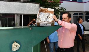 Hombre de pie frente a un maquina que tritura papeles