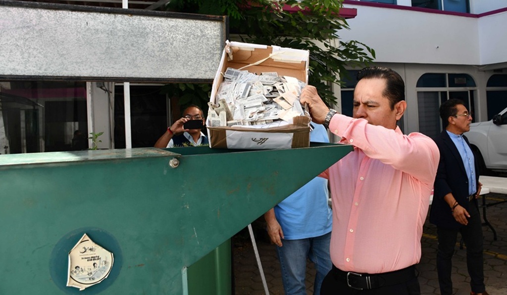 Hombre de pie frente a un maquina que tritura papeles