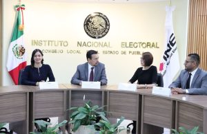 dos mujeres y dos hombres sentados detrás de ellos el escudo nacional
