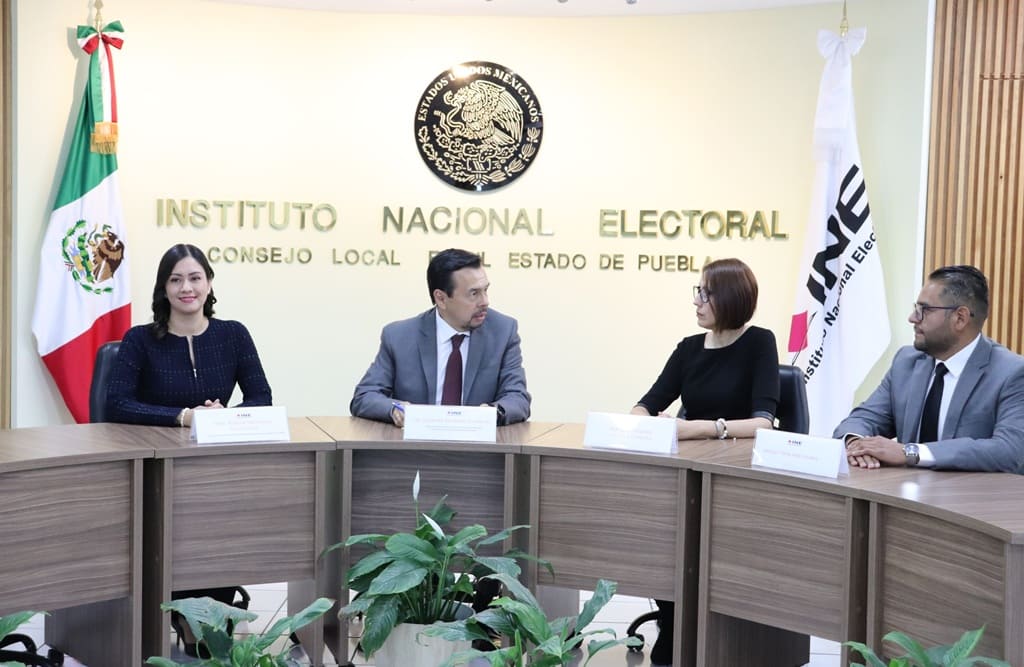 dos mujeres y dos hombres sentados detrás de ellos el escudo nacional