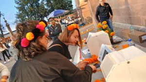 mujeres con disfraz de calavera votando en una maquina digital