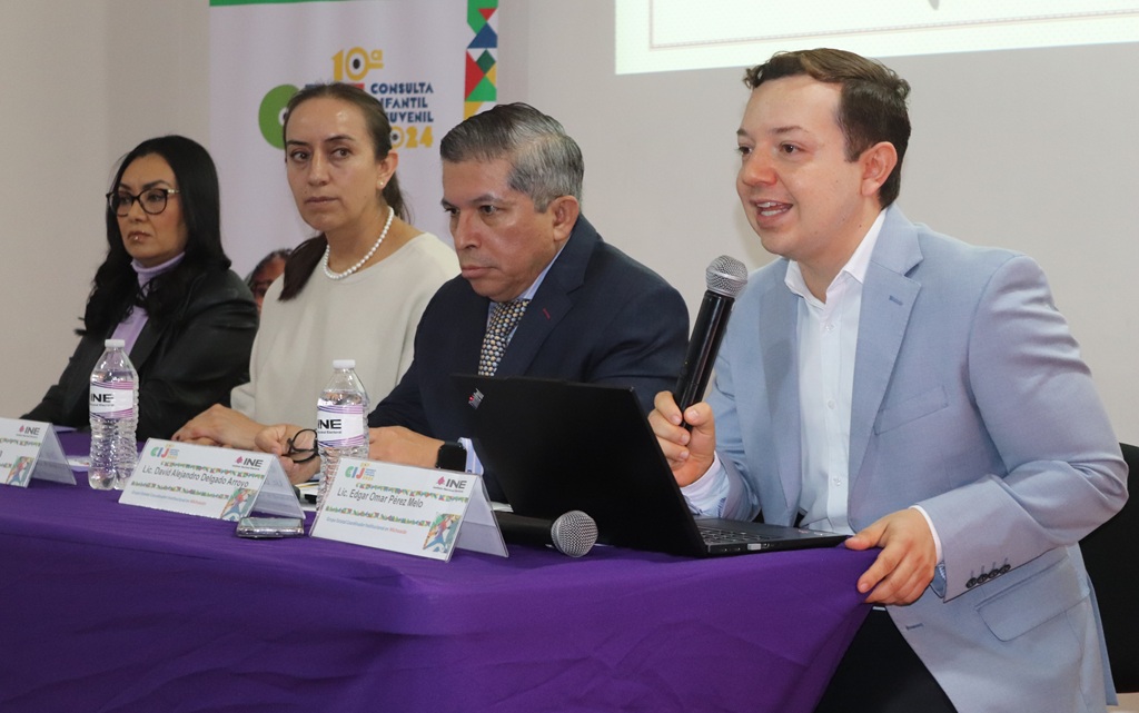 Dos mujeres y dos hombres sentados, uno de ellos, habla con micrófono