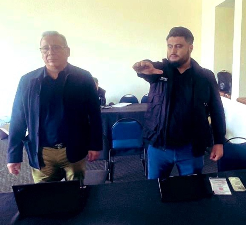 dos hombre de pie, uno de ellos, con el brazo derecho levantado al frente